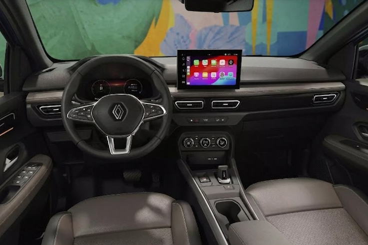 Vista frontal del habitáculo de un Renault Kardian Techno 200, mostrando el panel de instrumentos totalmente digital, el volante multifunción con el nuevo logo de Renault y una pantalla táctil central activa con interfaz Apple CarPlay. La consola central elevada incluye un selector de marchas e-shifter, freno de mano eléctrico y carga inalámbrica, enmarcada por asientos tapizados en cuero gris y tela texturizada.